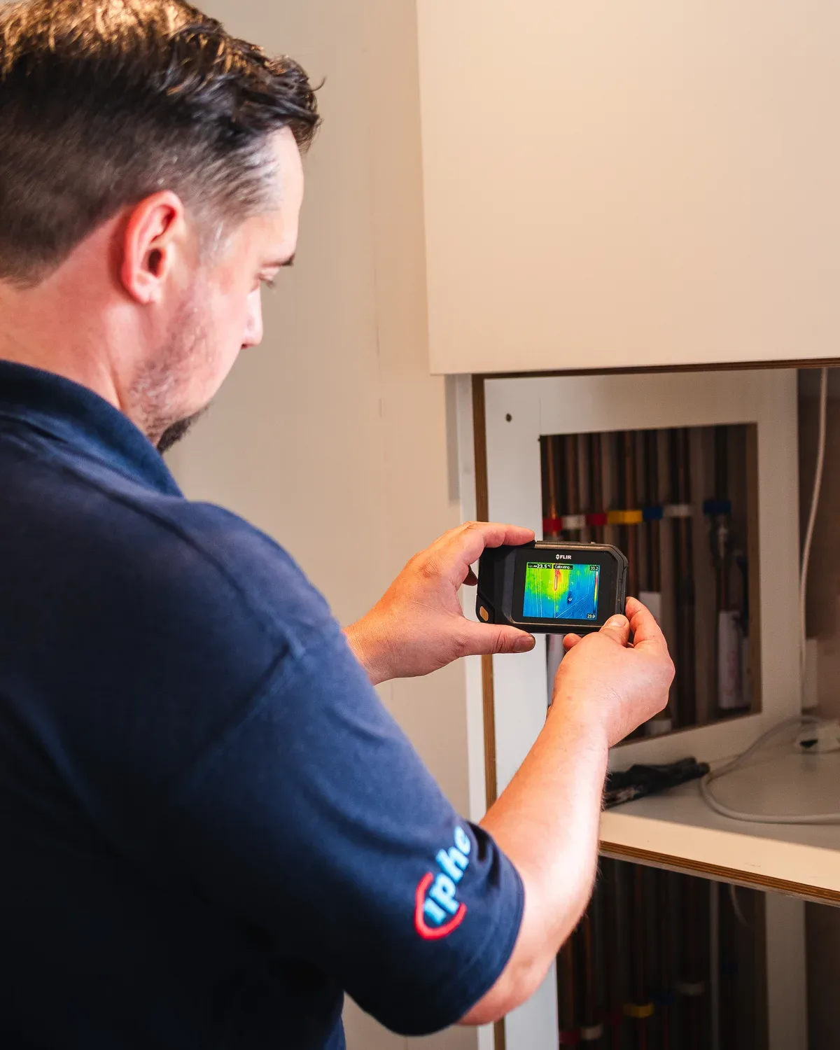 ADI engineer examining domestic pipework with a thermal imaging camera